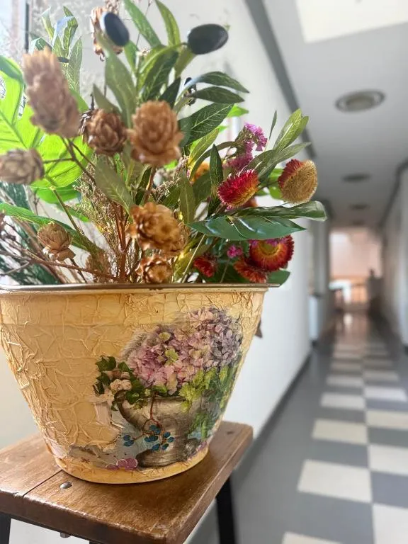 Pasillo del hotel con maceta decorativa y flores secas